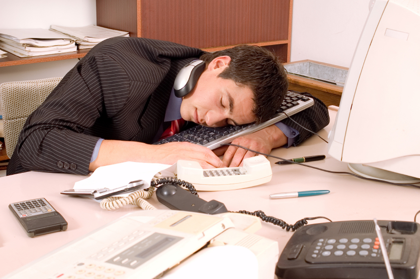 Businessman sleeping in his office at table with computer